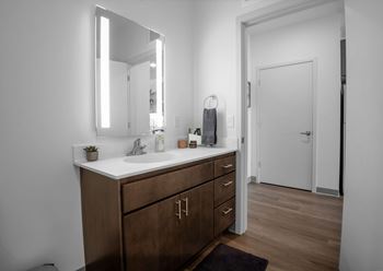 A bathroom with a sink, mirror, and wooden cabinets.